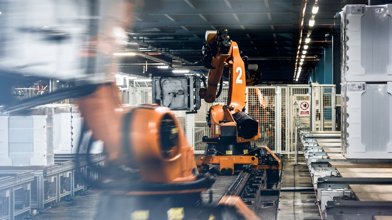 Industrial robots in an automated factory efficiently handle and move large white containers on a production line.