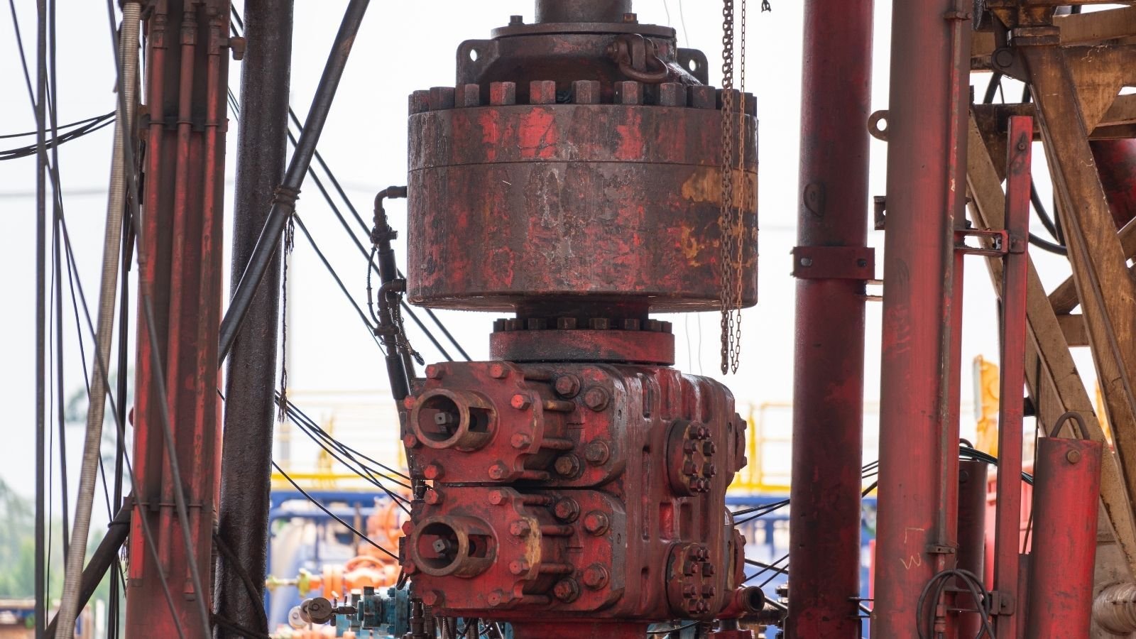 Close-up of a red blowout preventer in an oil rig, featuring cylindrical components and pipes, conveying industrial strength and precision.